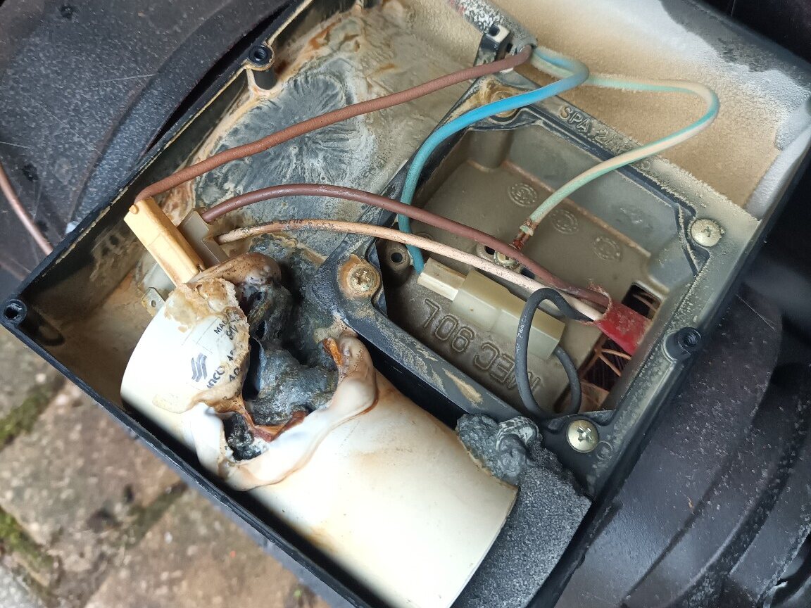 Melted hot-tub pump capacitor showing severe heat damage inside the pump terminal housing
