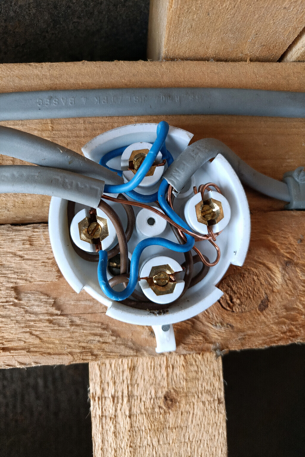 Lighting-point junction box with its lid missing and the internal conductors and terminals exposed